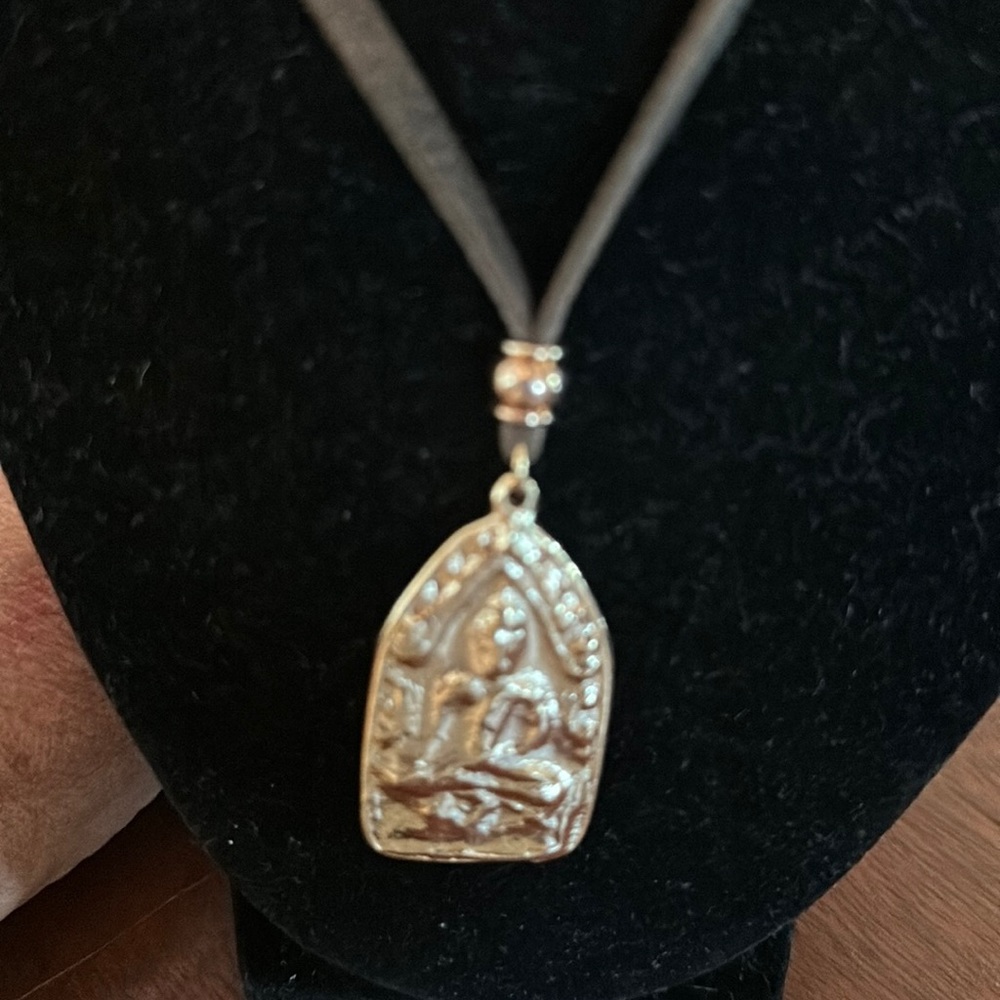 Mr. Ettija Buddha necklace on a suede